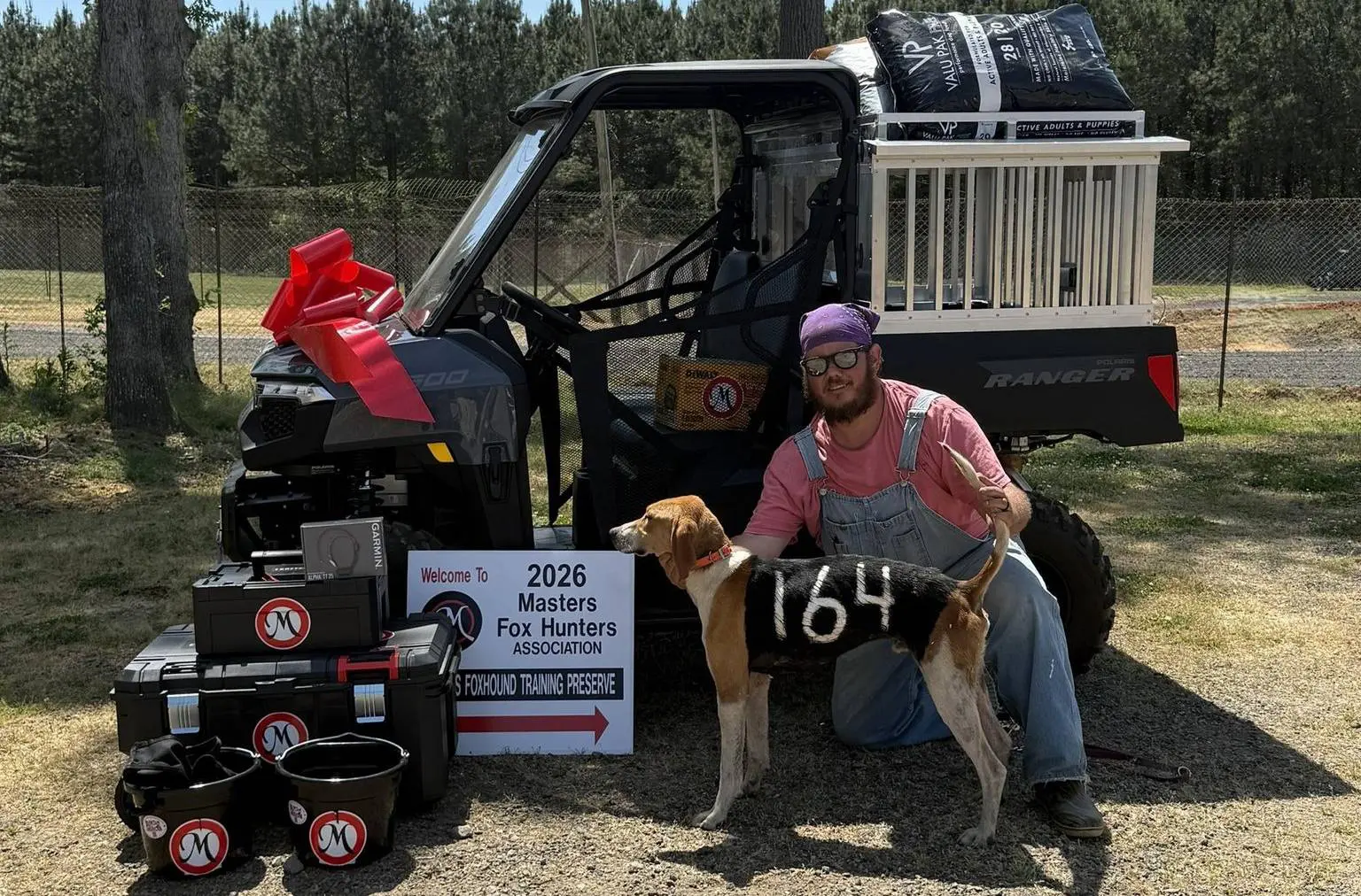 Man with dog and utility vehicle outdoors.