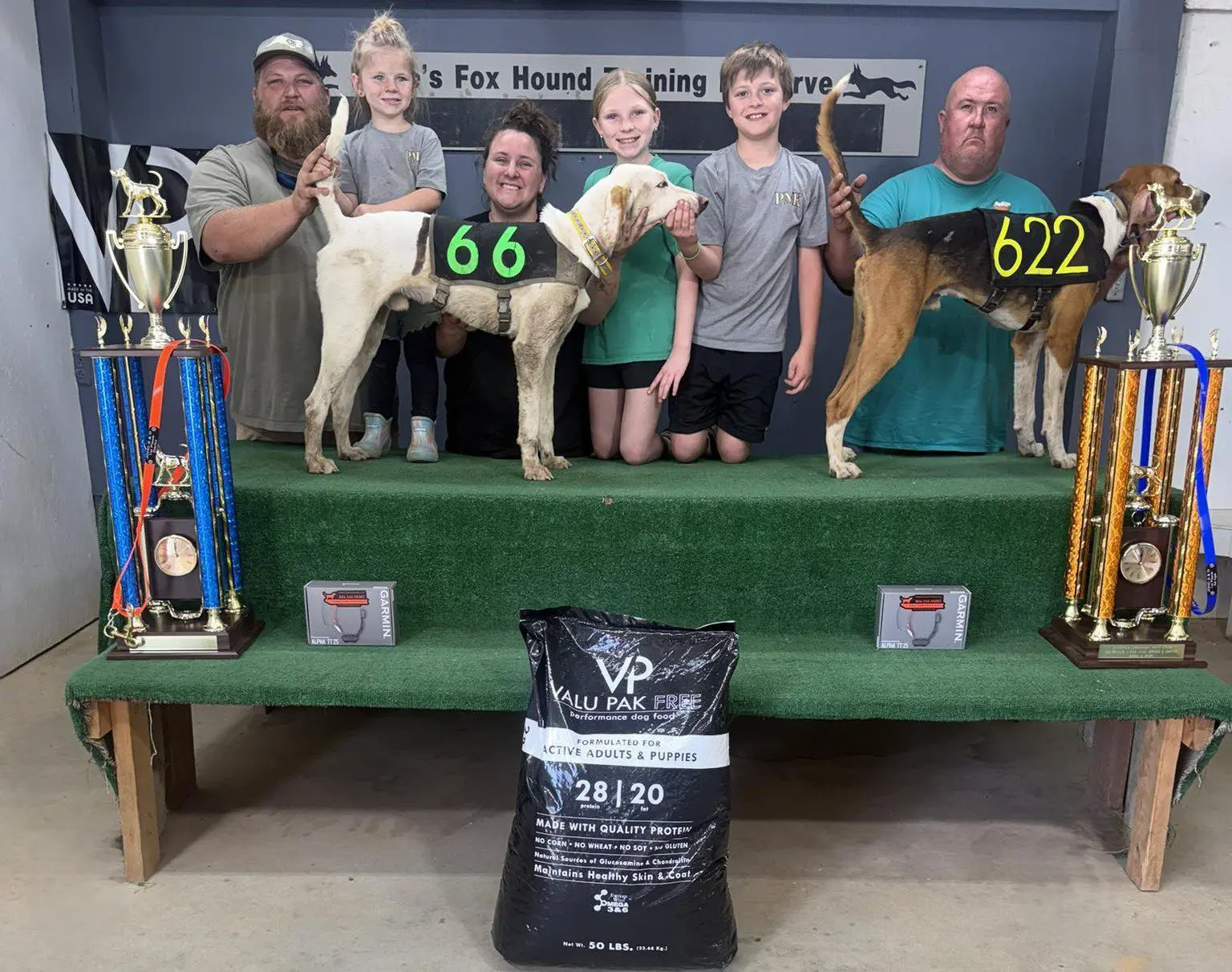 People with hounds and trophies on podium.