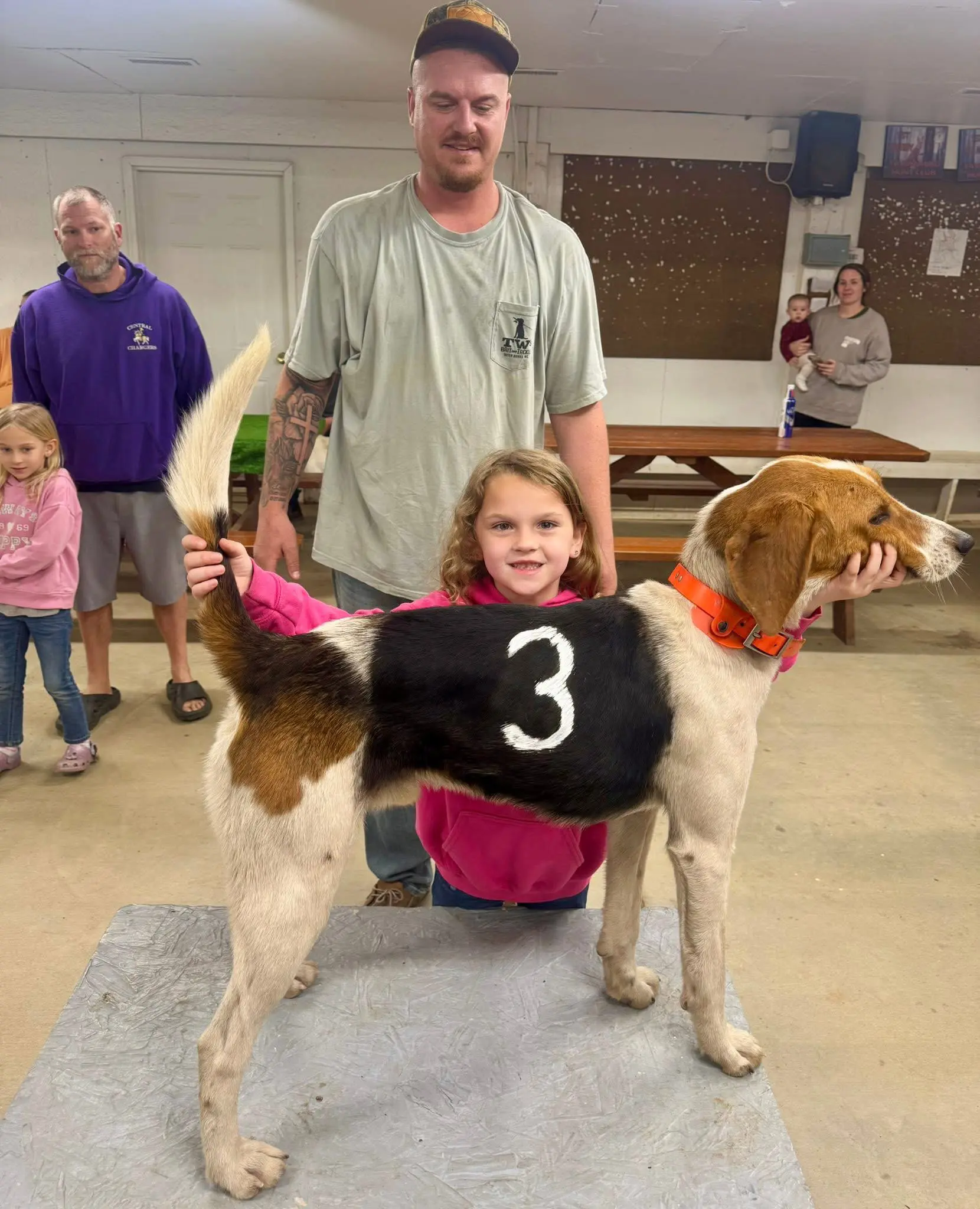 Child and adults with numbered hunting dog.