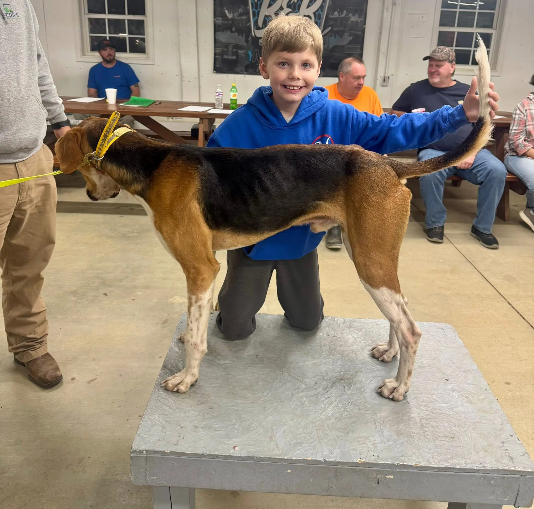 Child posing with a dog on table.