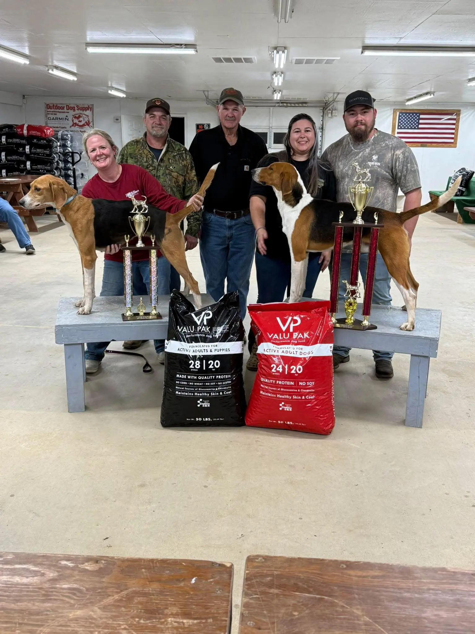 People posing with dogs and trophies indoors.