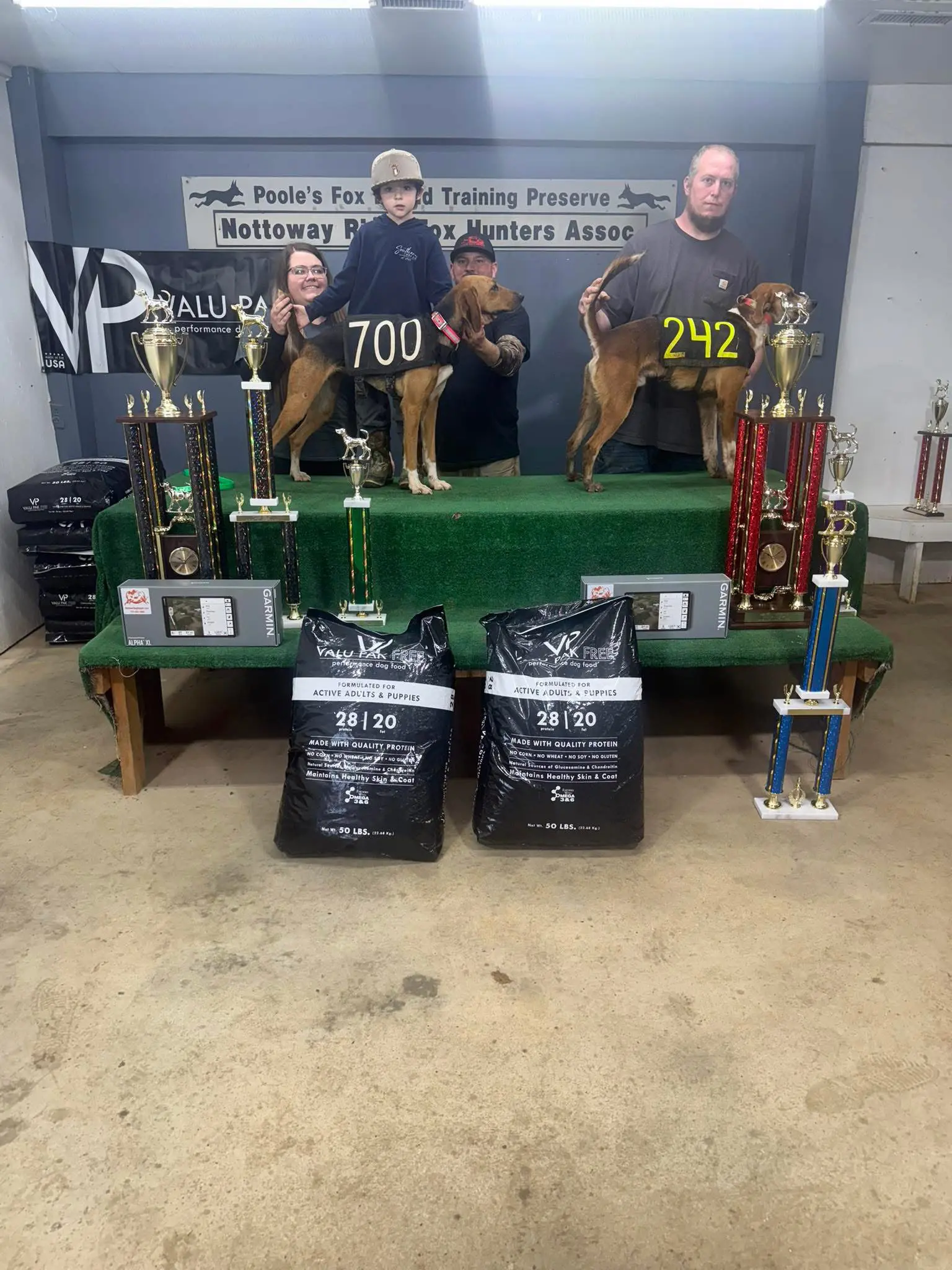 People with dogs and trophies on stage.