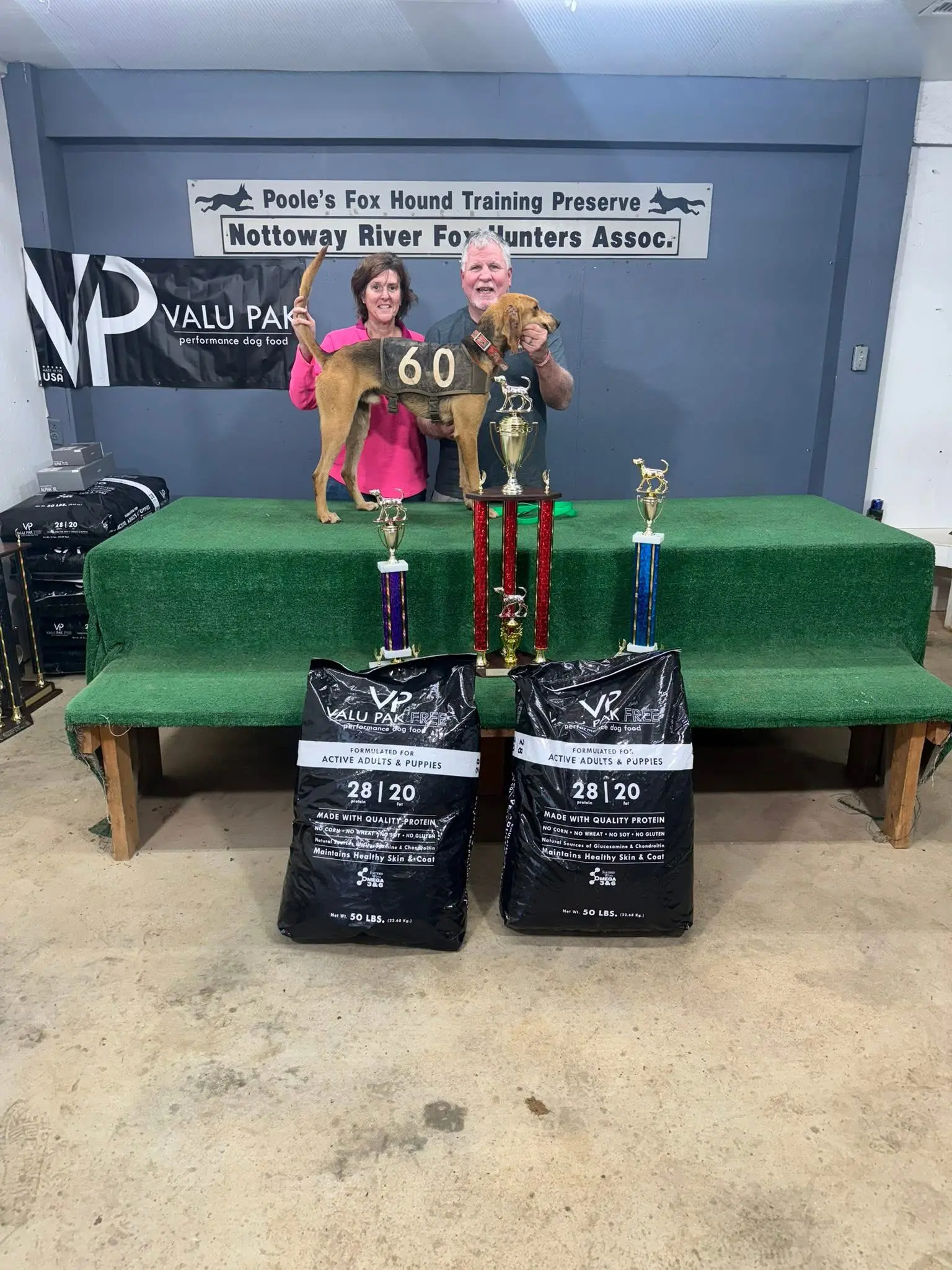 Winners with dog and trophies on stage.