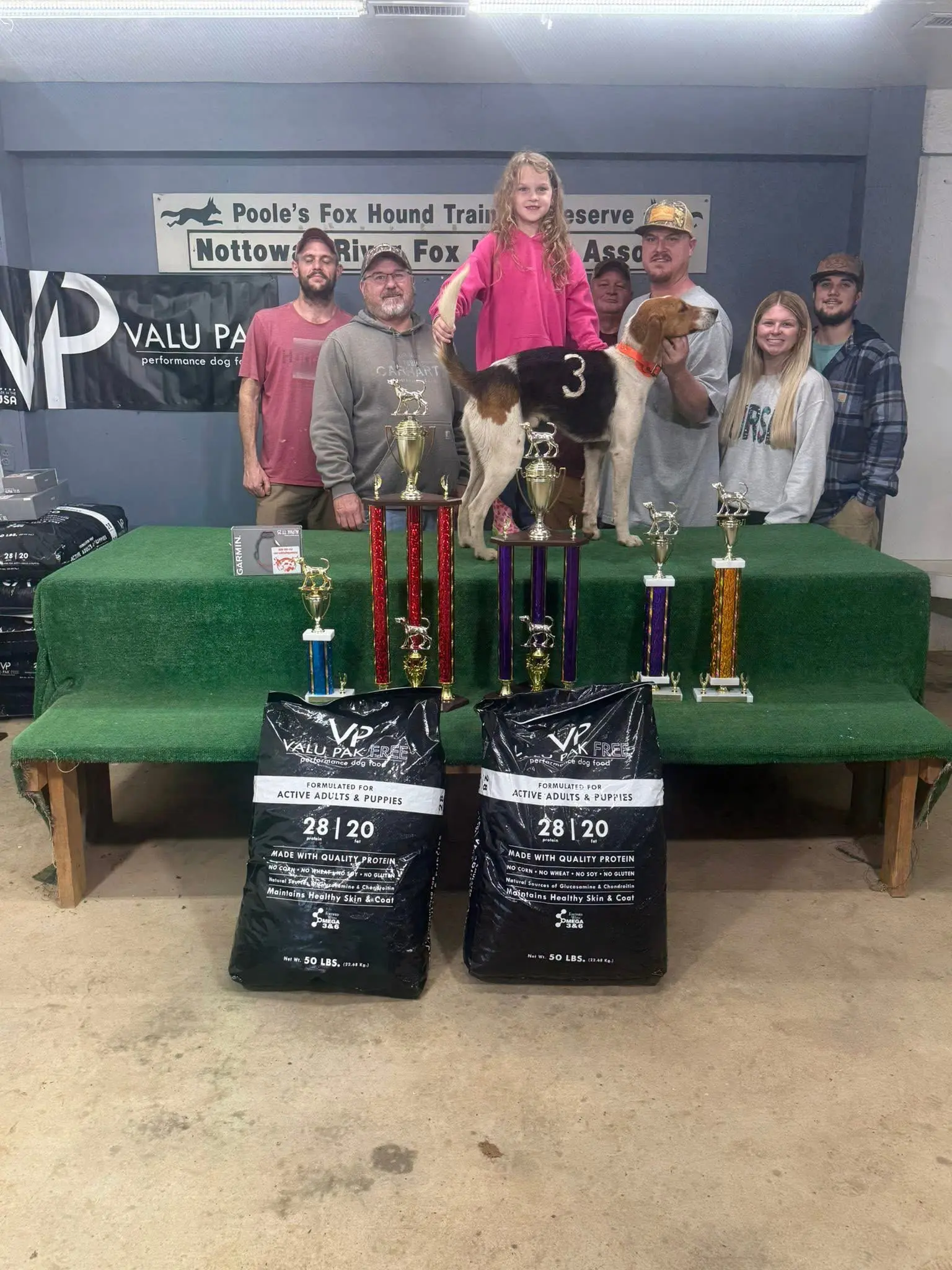Group with dog and trophies on display.