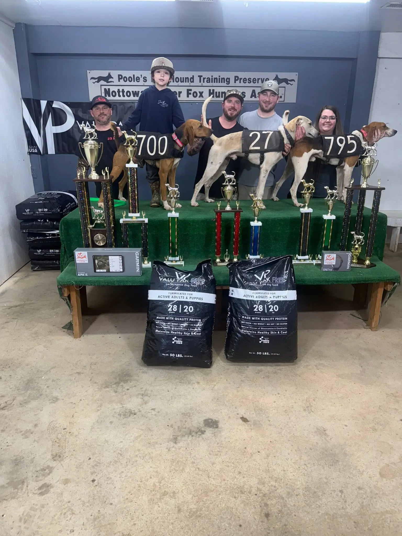 People with dogs and numerous trophies displayed.