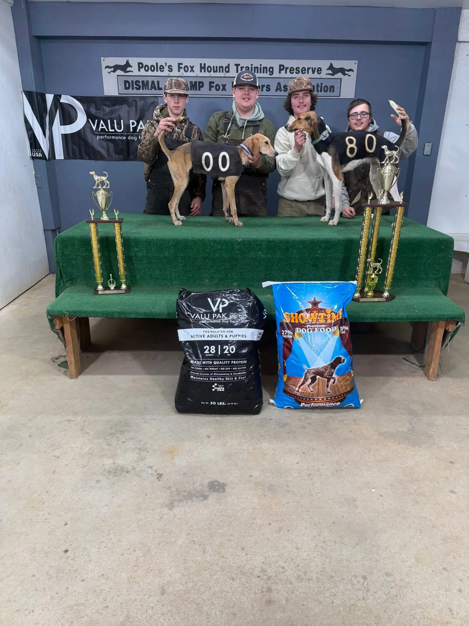 Four people with dogs and trophies.