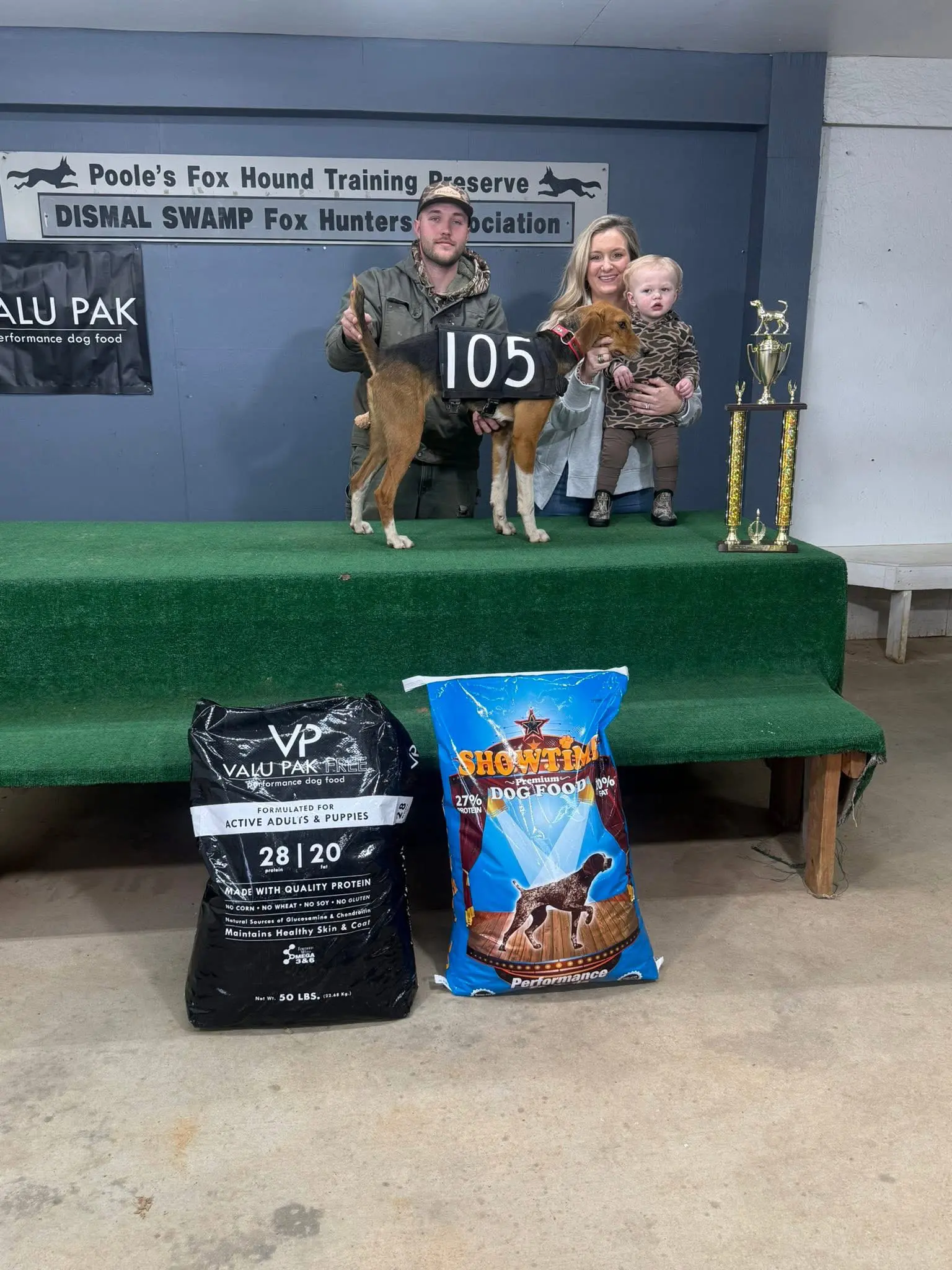 Family with dog and trophies on stage.