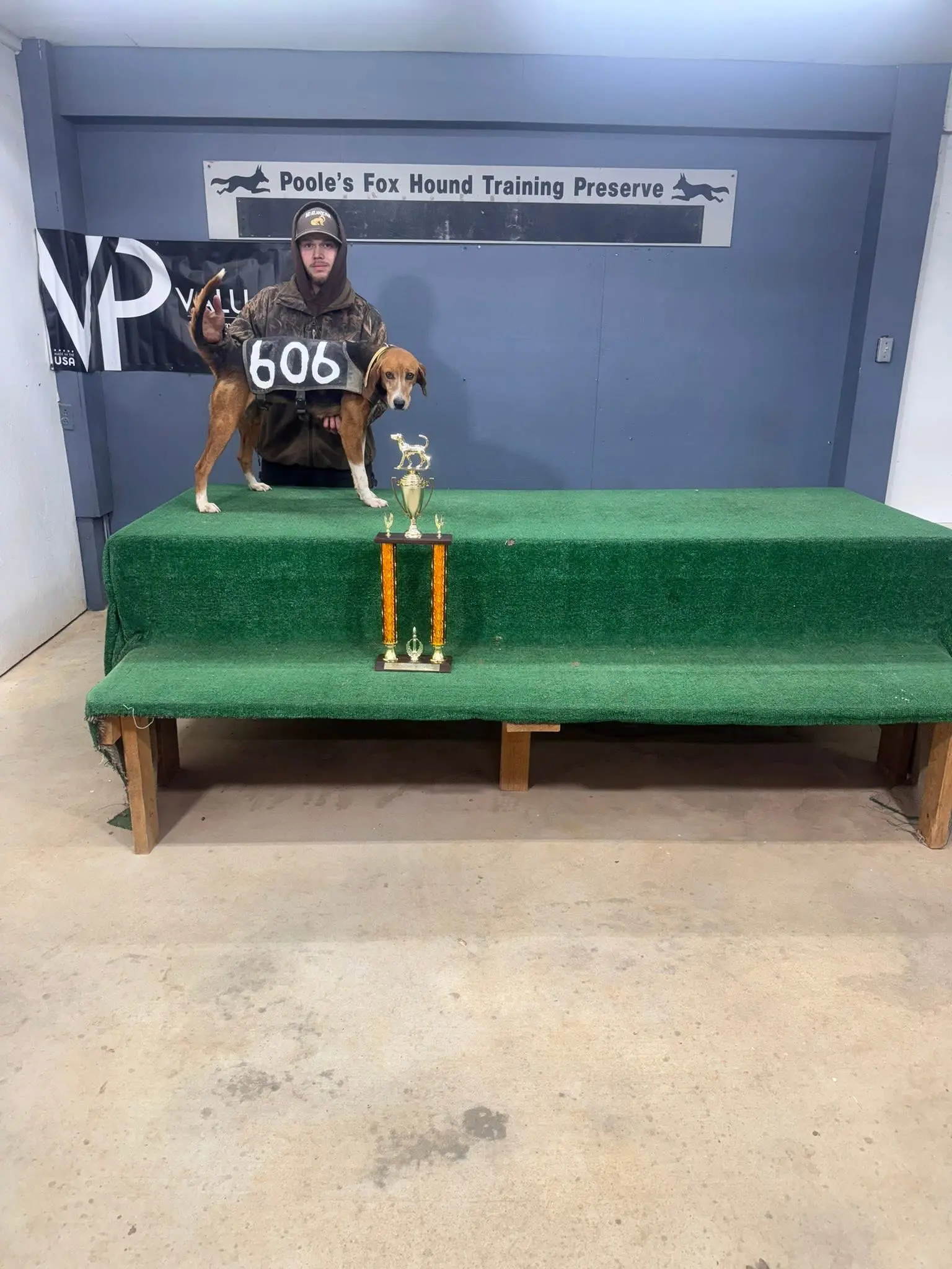 Hunter with dog and trophy on platform.