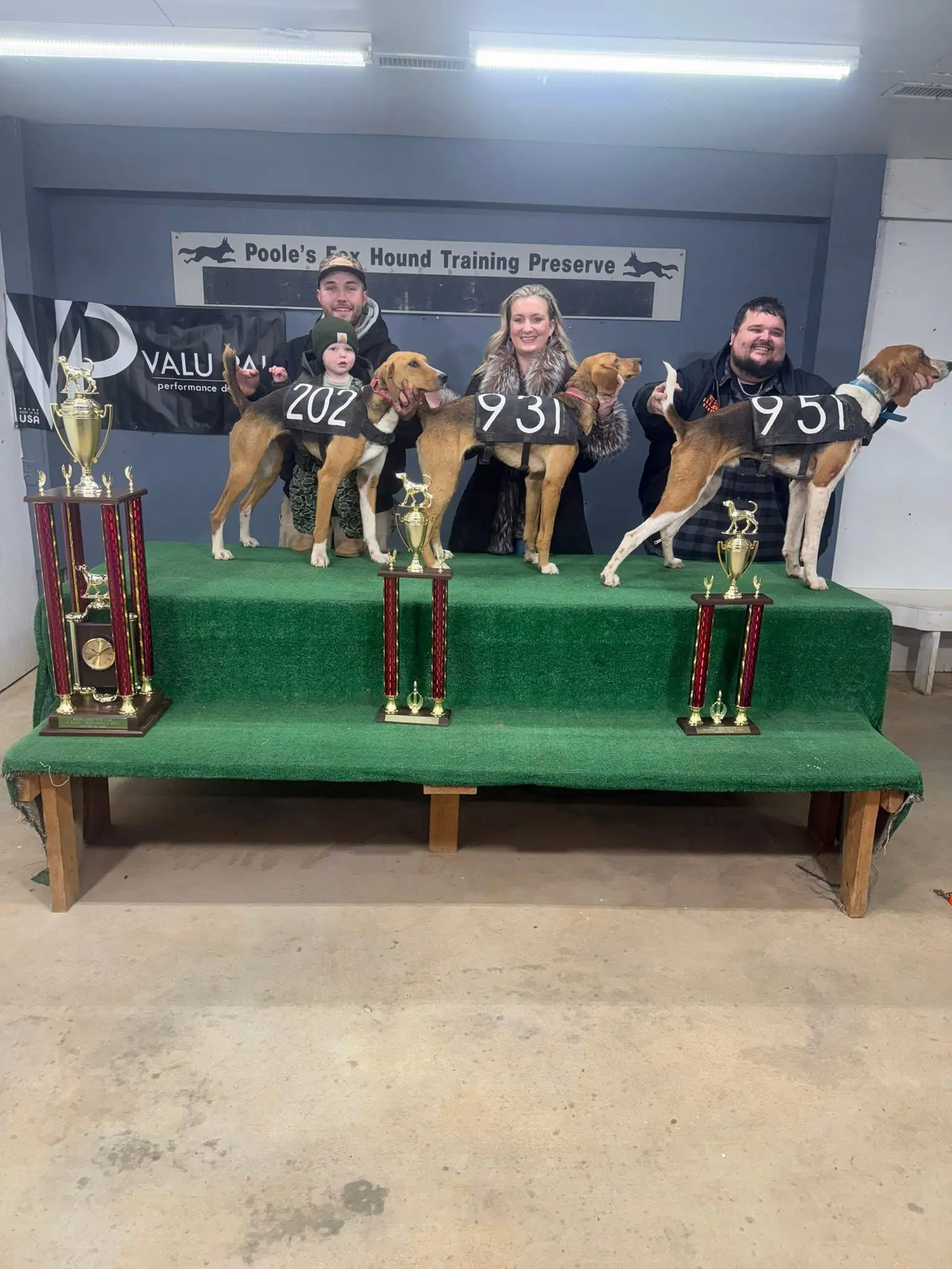 Three people with hounds and trophies.