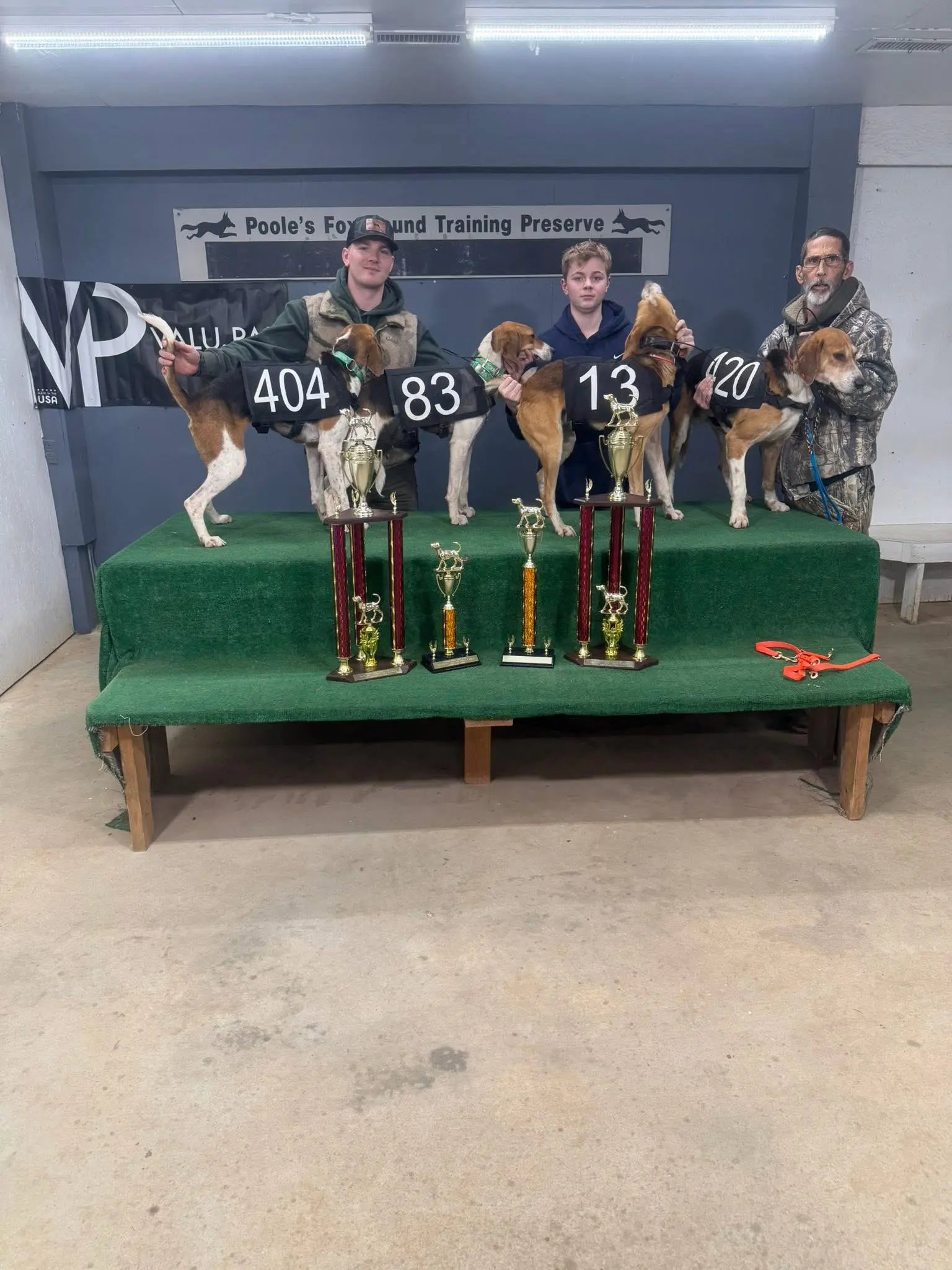 People posing with dogs and trophies indoors.