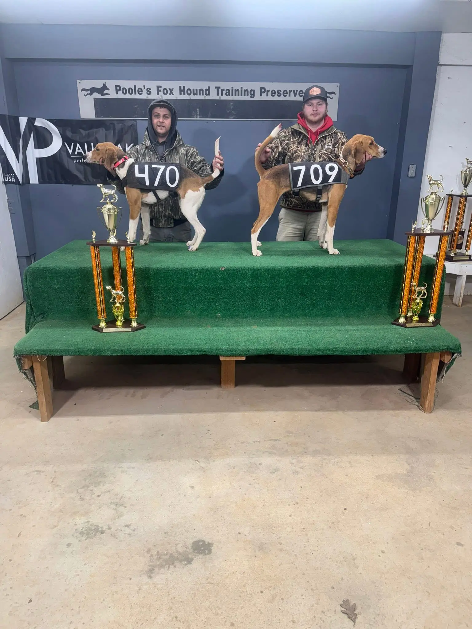 Two men with dogs and trophies displayed.
