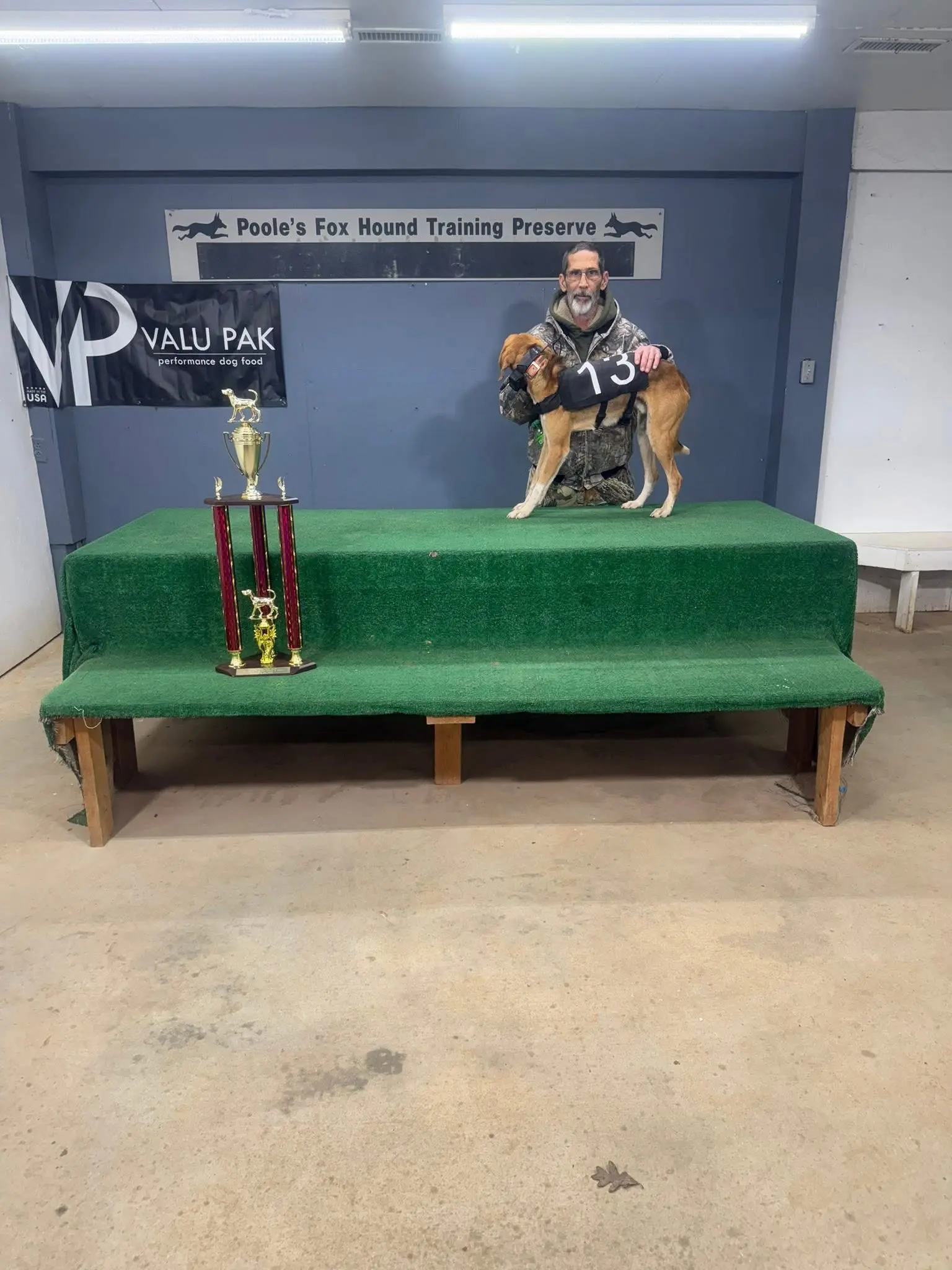 Man and dog on podium with trophies.