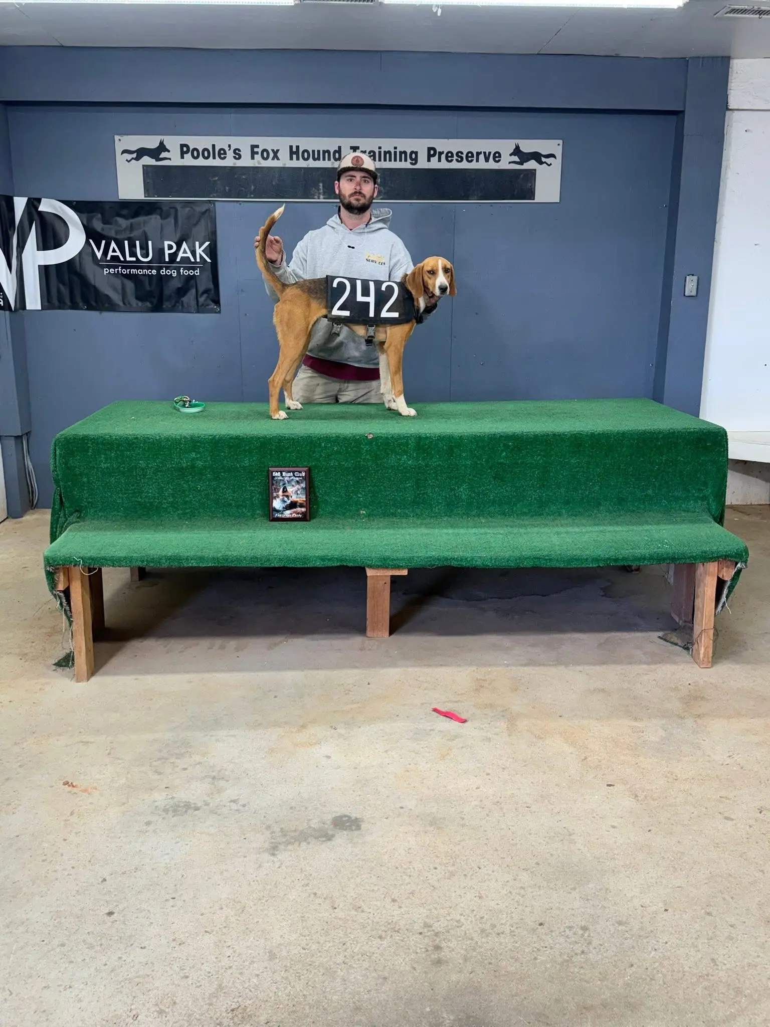 Man with dog on green platform indoors.