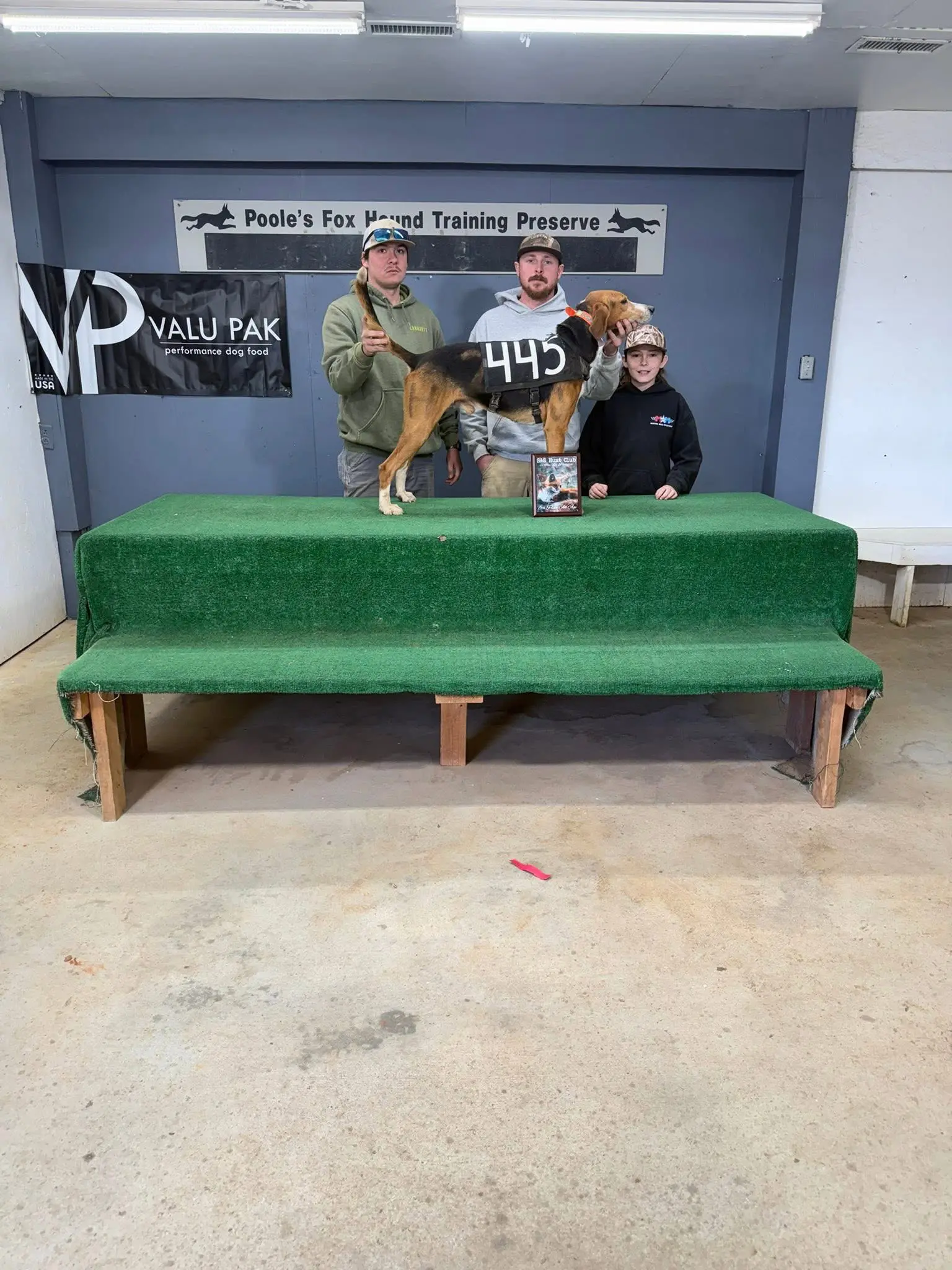 Three people with a dog on table.