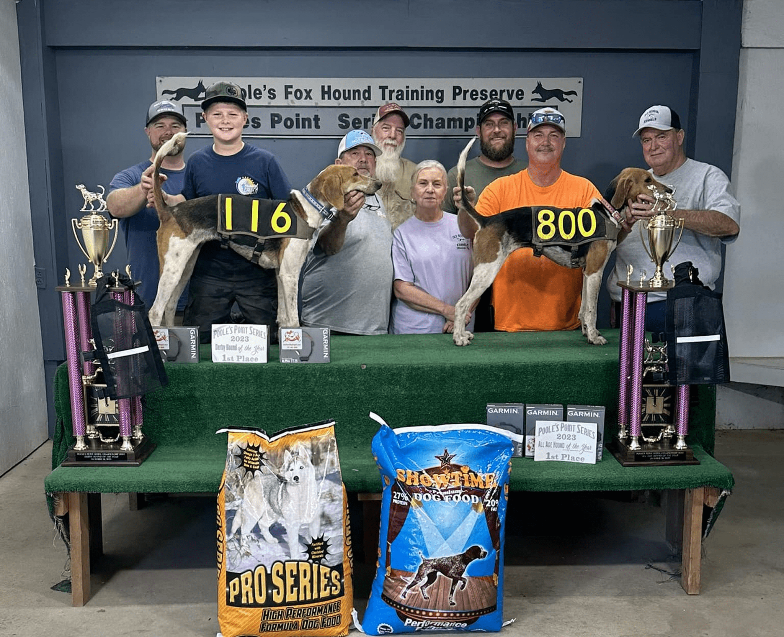 Group with hounds and trophies at event.