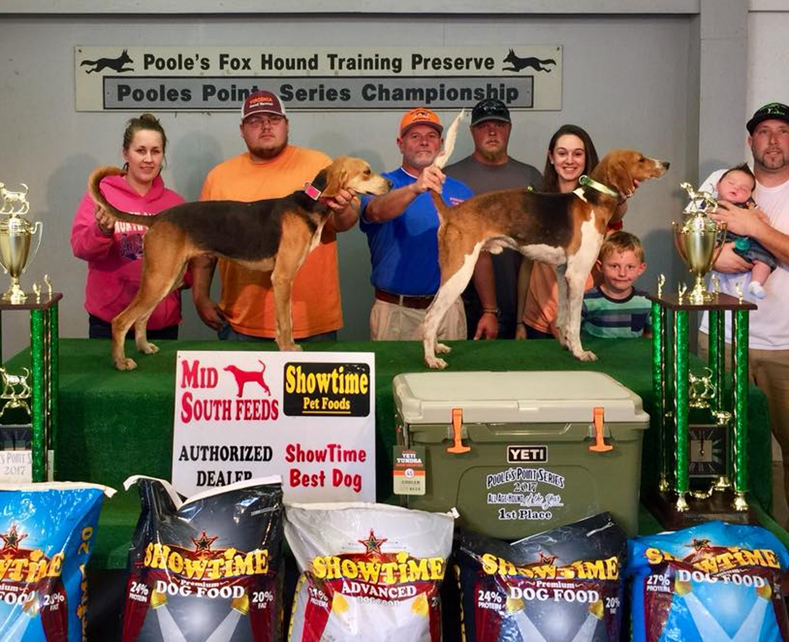 People with dogs and trophies at championship.