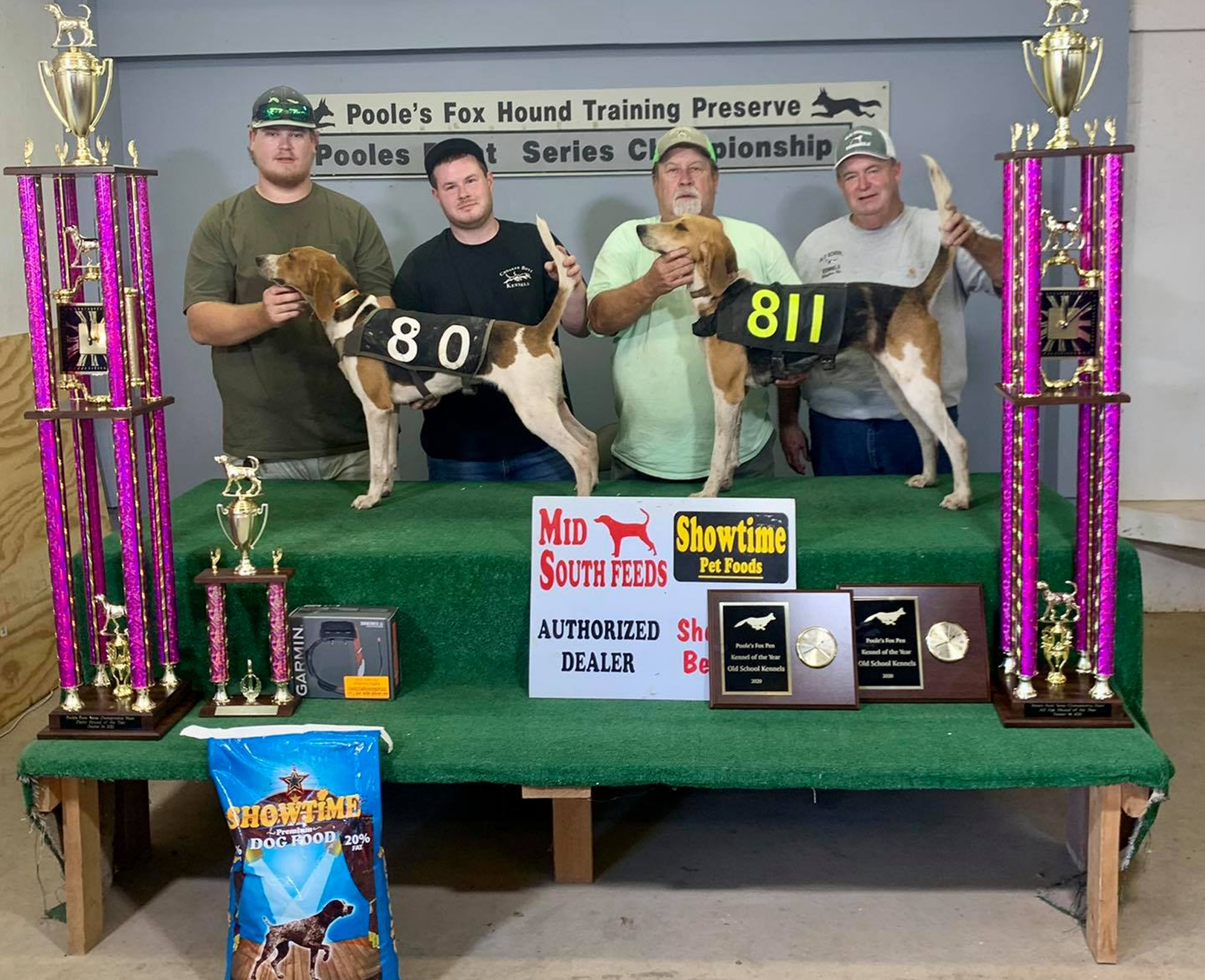 Two men with dogs and trophies displayed.