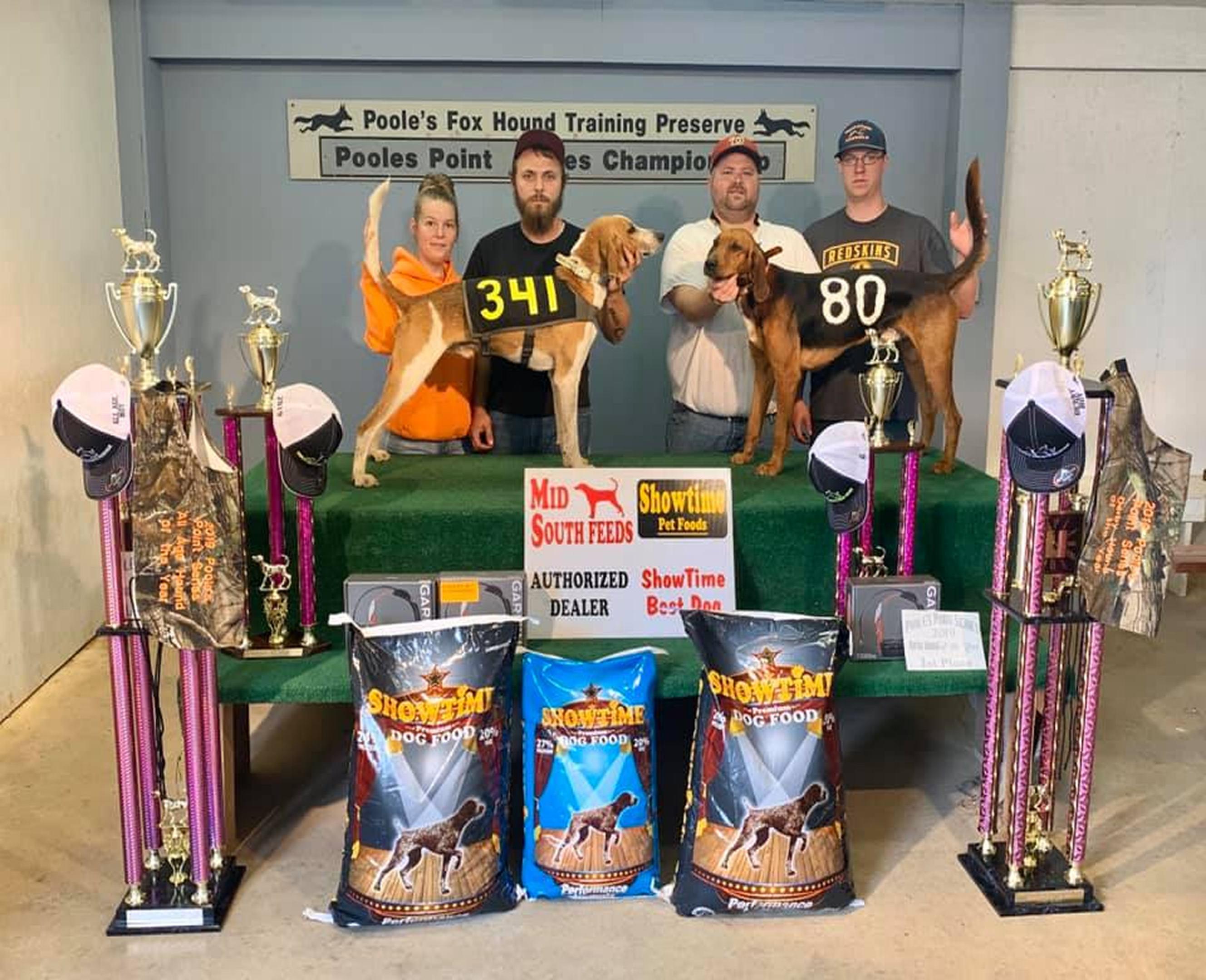 People with dogs and trophies at competition.