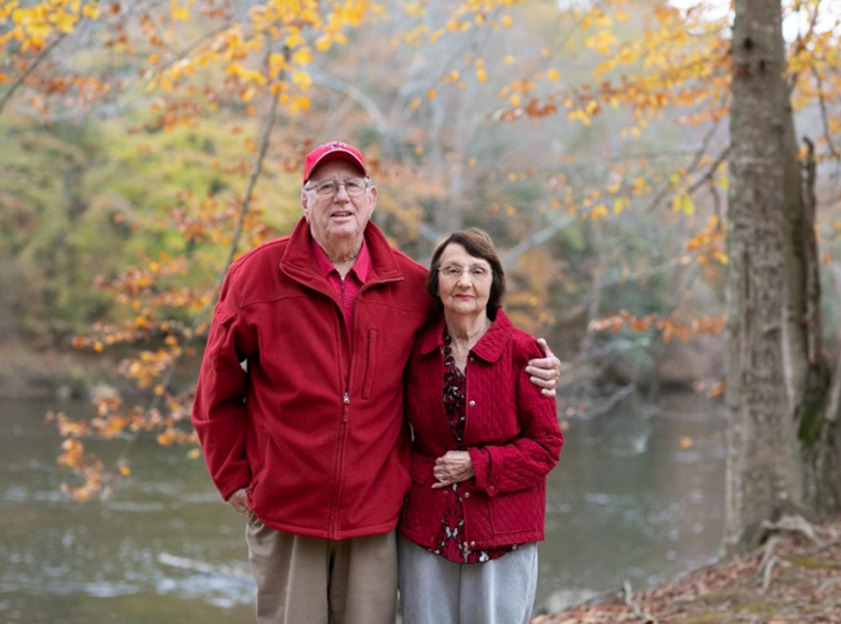 Seniors embracing near autumn river